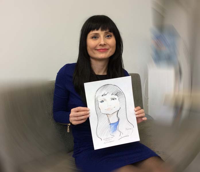 девушка в синем платье позирует шаржисту на корпоративе